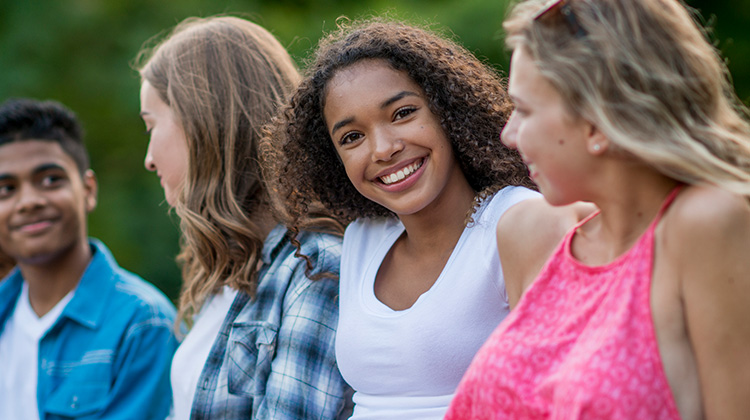 teenage girl smiling while sitting with friends