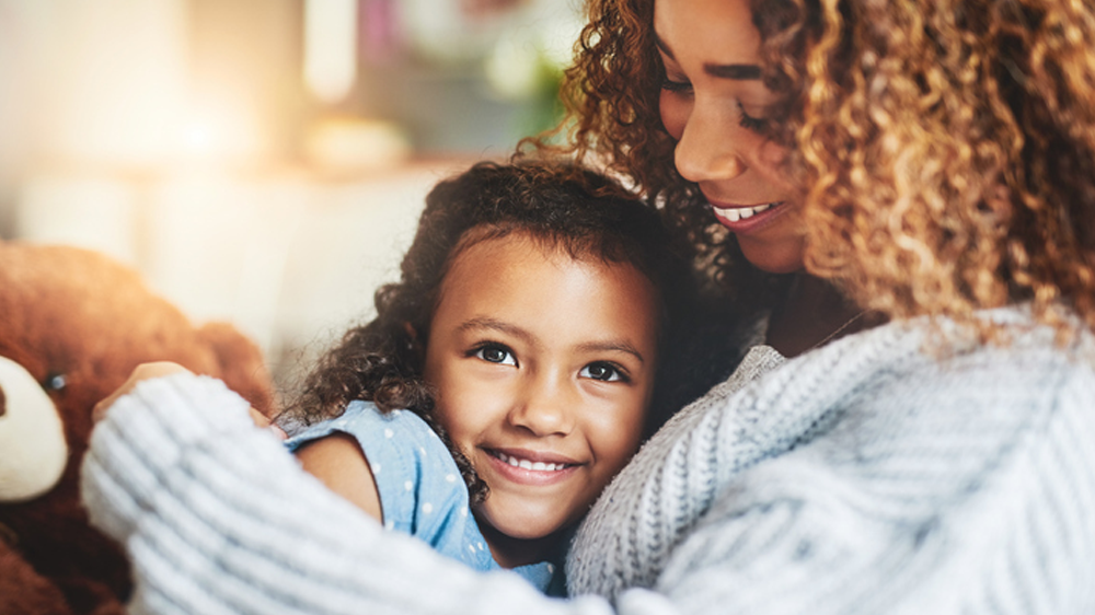 caramel skin mother hugging her smiling daughter