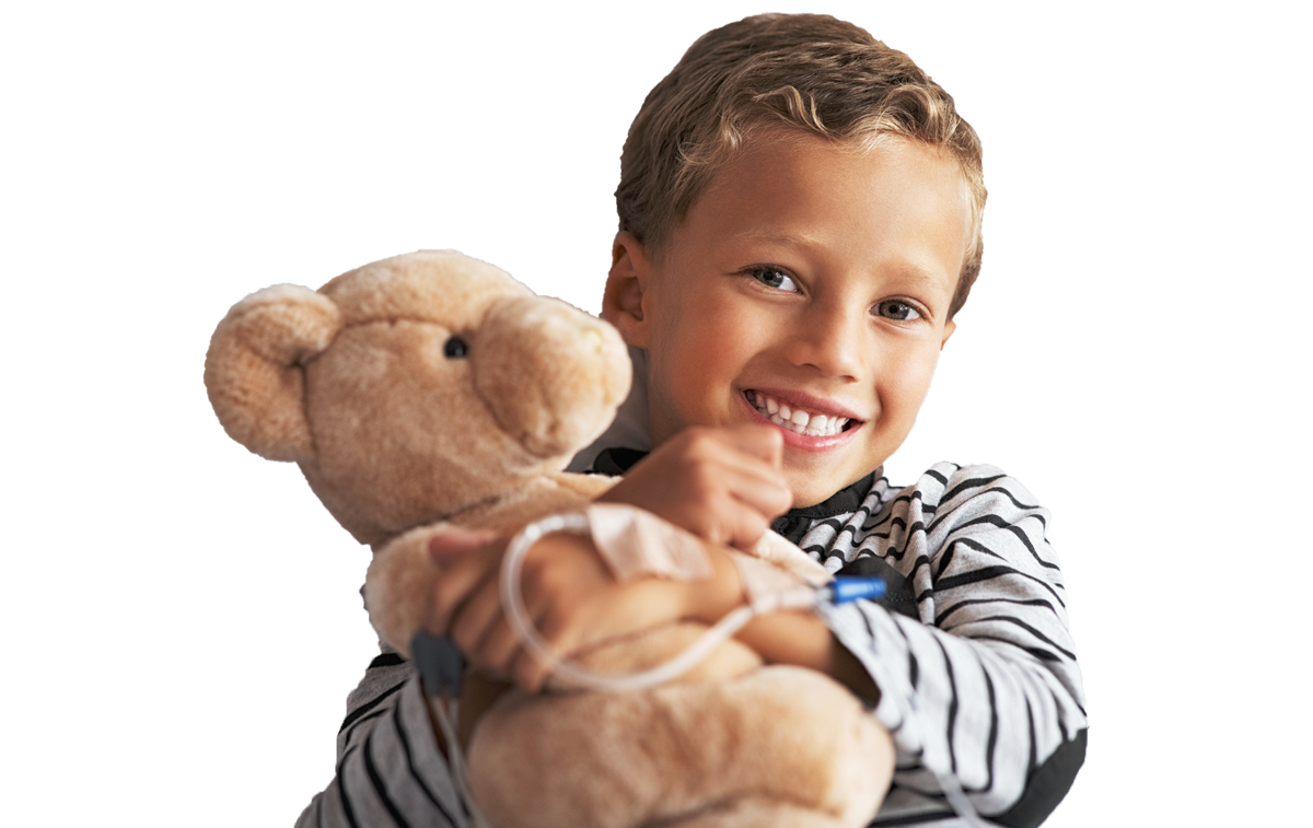Boy smiling with an IV holding a bear in a hospital bed