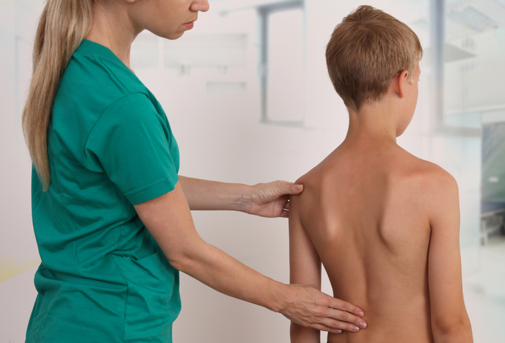 Terapeuta haciendo un examen de la espalda a un niño.