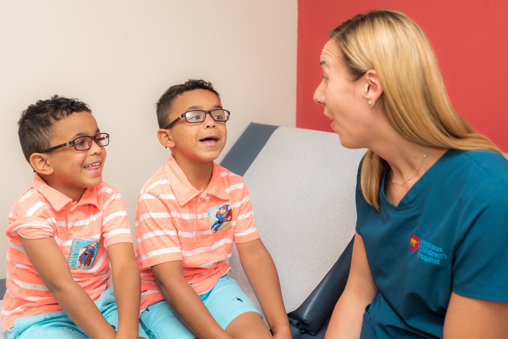 twin brothers with BWS smiling at speech therapist.