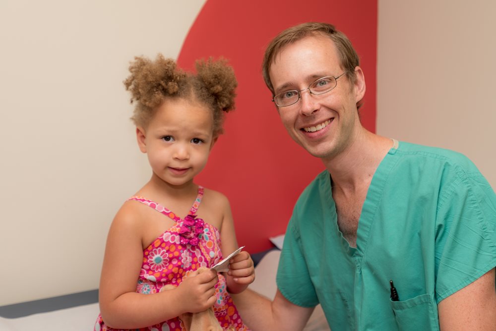 Dr. and curly haired girl smile for camera.