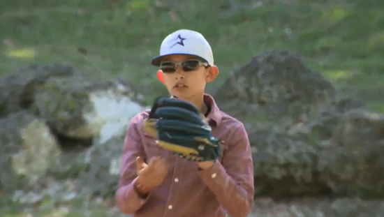 Grant with a baseball cap and mitt playing catch.