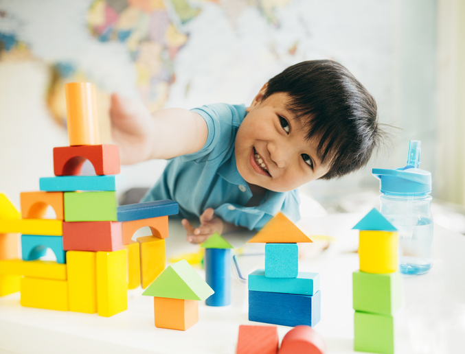 toddler playing with wood building blocks.