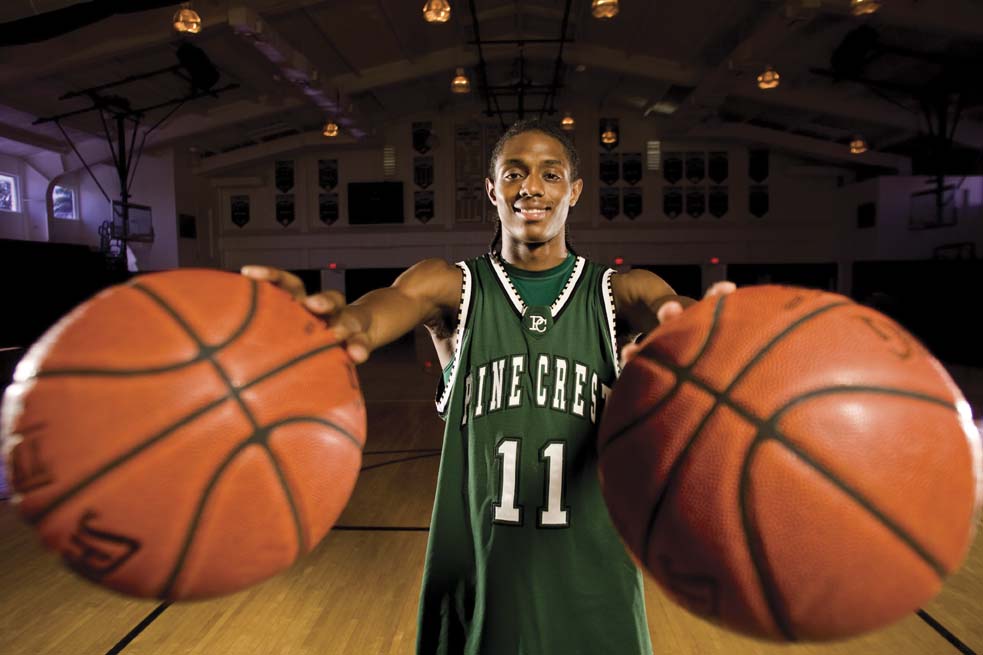 Brandon holding two basketballs, one in each palm of his hand. 