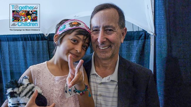 Maya haciendo el signo de paz con la mano izquierda junto a Michael Duchowny, MD