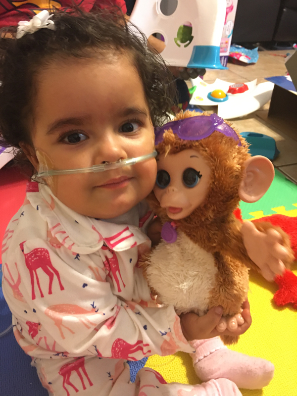 Angelica holding a stuffed doll of a monkey while posing for the camera. 