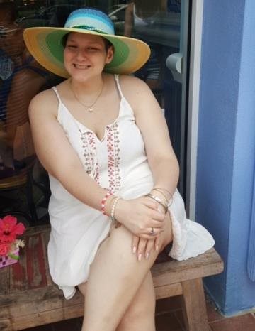 Ruby in summer cloths sitting on a wood bench. 