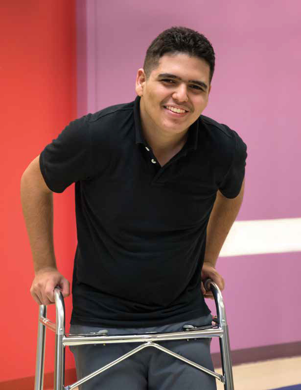 Asnay smiling while standing up with a walker