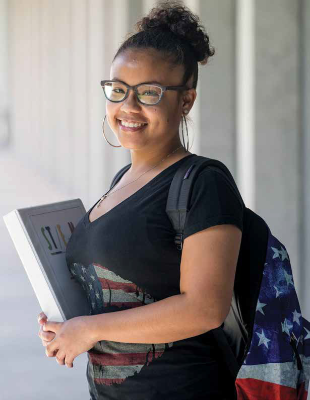 Sydnie holding a binder and wearing a back pack.