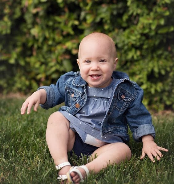 Alyssa Caulley's daughter outside sitting in the grass as a baby.