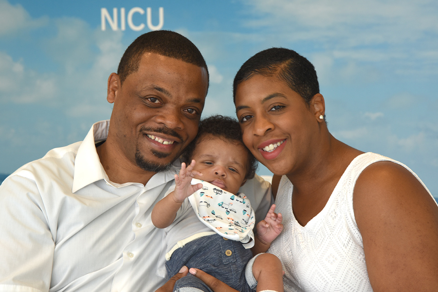 baby Logan with his parents in front of the NICU