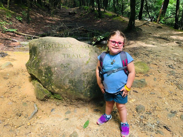 Almudena standing in front of a bolder on a hiking trail. 