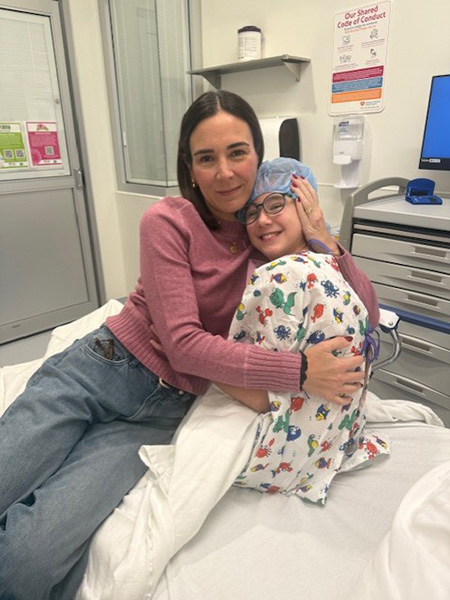 victoria post-surgery in her hospital bed held by her mother.