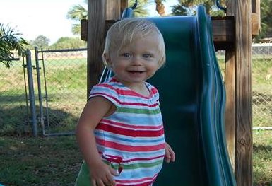 Brenna standing in front of a green park slide.