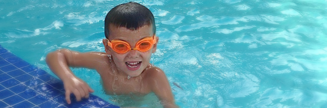 Felix playing in the pool wearing orange pool goggles. 