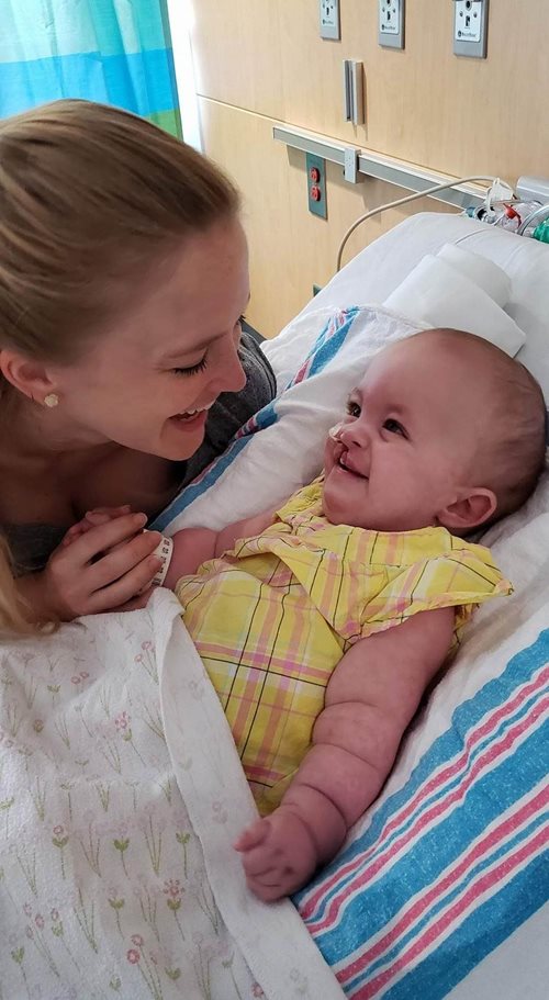 Heidi smiling and holding her mother's hand in hospital bed