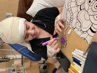 Ella coloreando mientras descansa en una cama de hospital
