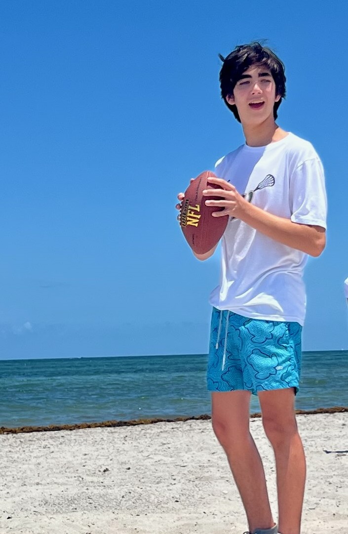 Tomas sosteniendo un balón de fútbol en la playa.