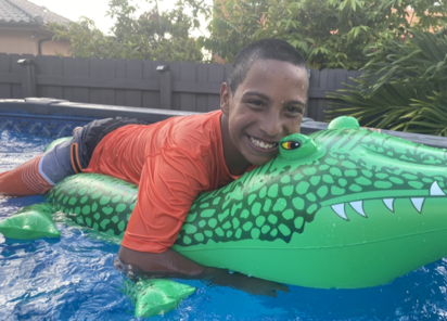 Jacob en una piscina sobre un flotador de cocodrilo