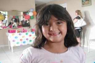 Janiery smiling while in front of what looks like a birthday cake table. 