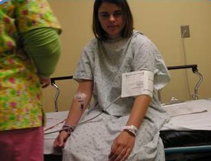 Jessica sitting up on a hospital bed having her blood pressure measured. 