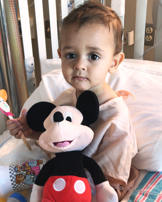 Leonardo with a Mickey Mouse stuffed animal sitting in his hospital bed. 