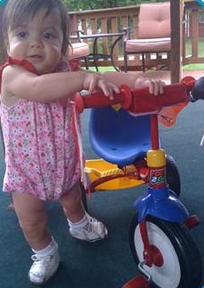 Baby Natalie playing with a tricycle