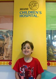 Caden while visiting the hospital posing in front of a hospital logo.