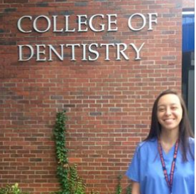 Christina outside of the College of Dentistry in medical scrubs.