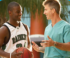 Daniel holding a basketball wearing his team uniform next to Dr. Burke. 