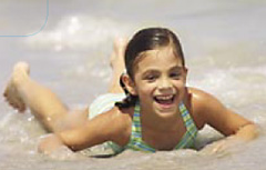 smiling Hannah on her belly in the water at the beach. 