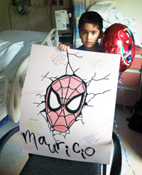 Mauricio in his hospital room holding up a spider man poster