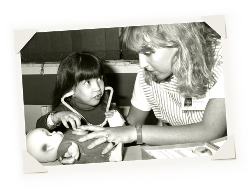 black and white photograph of child life specialist playing with a girl and her doll.