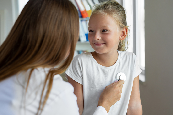 female doctor listens to girl's heart with stethoscope.
