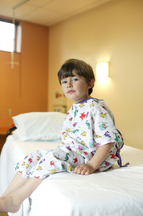 boy wearing hospital gown inside exam room.