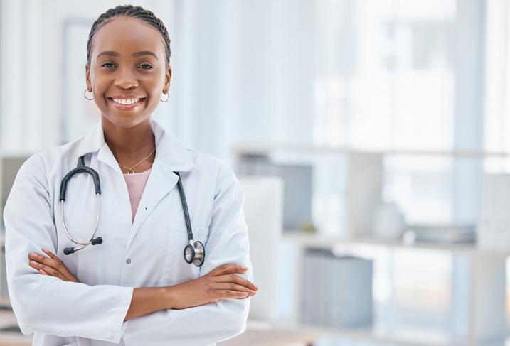 young female doctor smiling warmly with arms crossed.