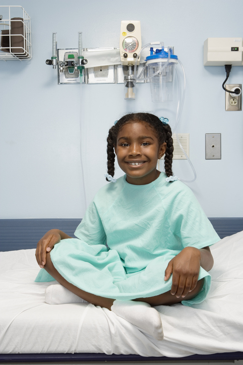 girl wearing light green hospital gown sitting.