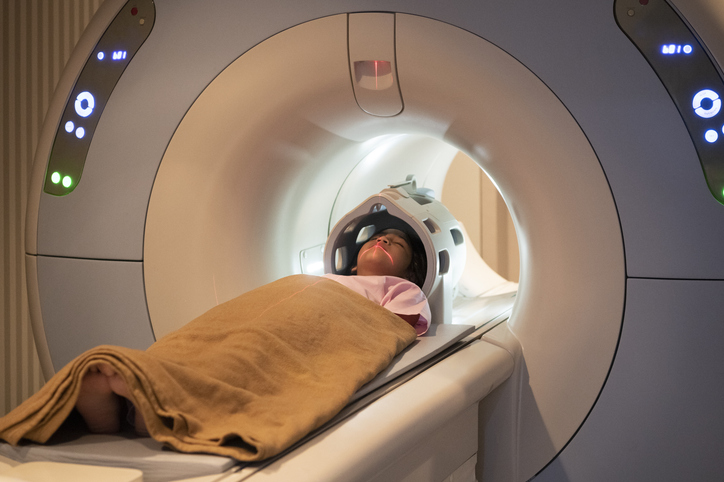girl laying very still on MRI tray with a blanket covering her.