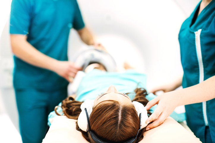 techs remove headphones of young girl laying down.