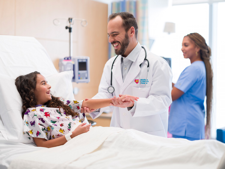 Doctor comforts girl at her hospital bed.