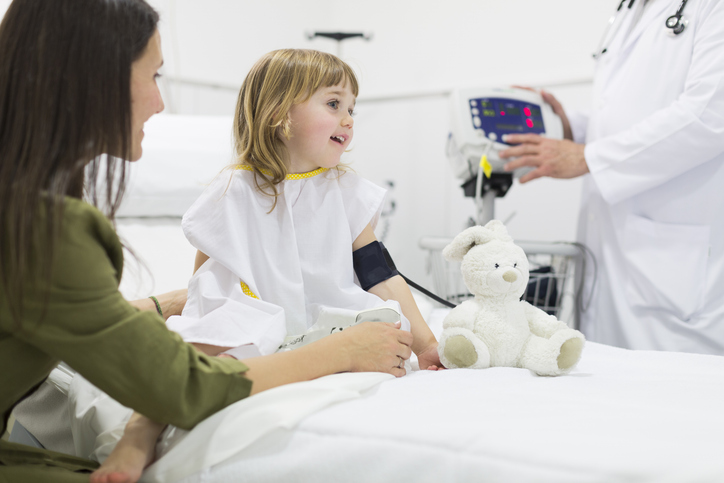 girl on hospital bed with pressure cuff on her arm.