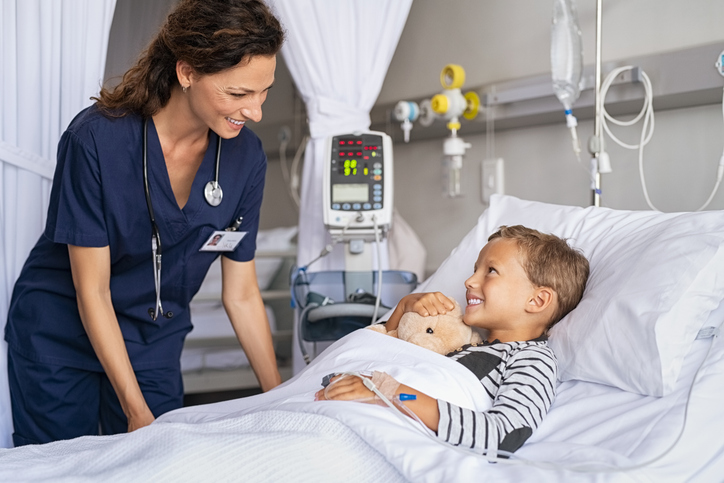 nurse checks in on boy at the hospital bedside.