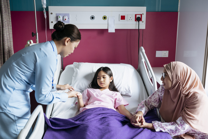 girl in hospital surrounded by nurse and mother.