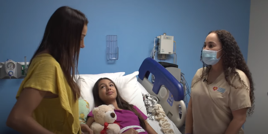salma is laying down on bed surrounded by her mother and sleep tech.
