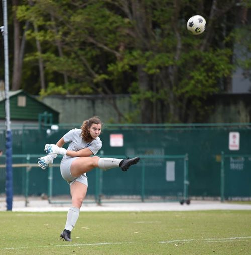 Stephanie pateando una pelota de fútbol en un partido.