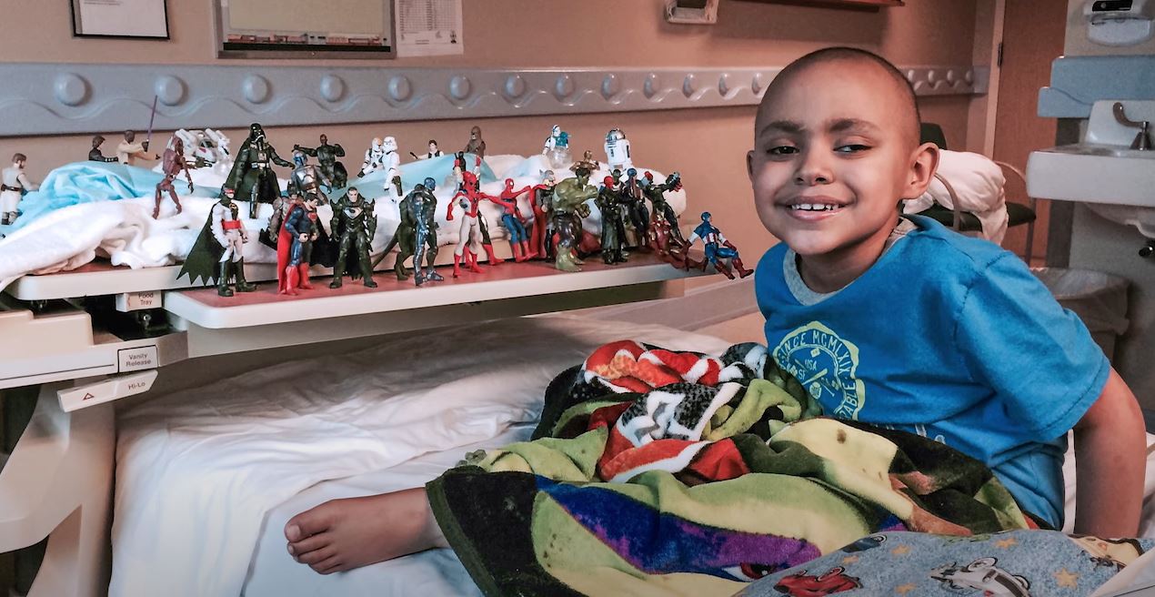 Juan Pablo playing in his hospital bed with super hero toys.