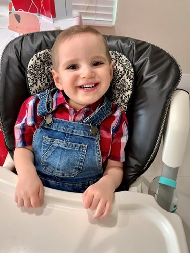 Matthew in a high chair smiling.