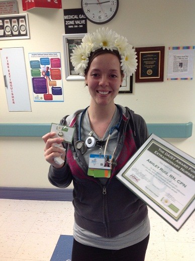 awardee wearing a headband of daisies, daisy award statue, and certificate.