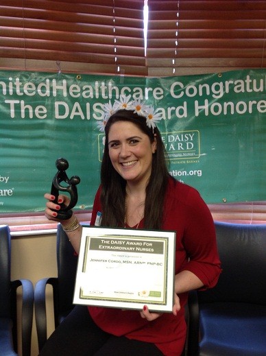 awardee wearing a headband of daisies, daisy award statue, and certificate.